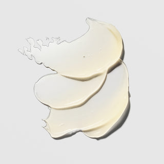 Hydrinity Luxe Lip Hydrator texture swatches showing layered translucent pale cream lip balm formula on grey background.