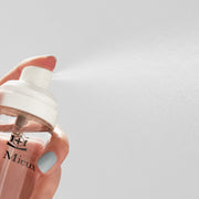 Hand spraying Le Mieux Essence Toner showing ultra-fine mist dispensed from clear spray bottle.