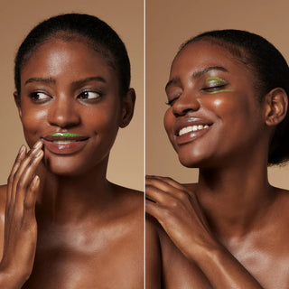 Model demonstrating Le Mieux Eye and Lip Cream applied to lips and eye area showing iridescent green pearl texture on deep skin tone.