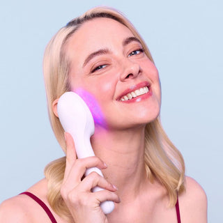 Lightstim for acne used by blonde woman, holding it against her cheek.