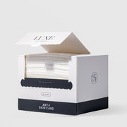 Art of Skin Care Luxe Eco Towels 50-count box open and dispensing soft white towels through a serrated tear slot, with the AS monogram logo on the side, displayed against a light gray background.