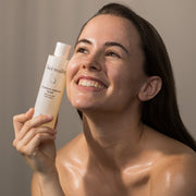 Smiling woman with hydrated glowing skin holding Face Reality Moisture Balance Toner – hydrating replenishing toner for dry skin