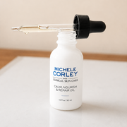 Michele Corley Clinical Skin Care Calm Nourish and Repair Oil 1 oz dropper bottle open showing clear facial oil on marble surface.