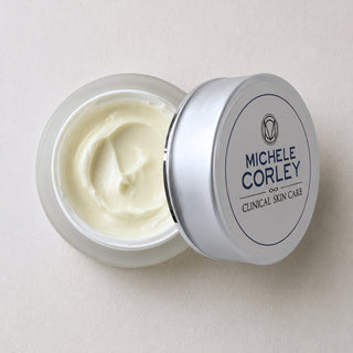 Michele Corley Clinical Skin Care Calming Moisture Cream open glass jar showing rich off-white cream with silver lid on white surface.