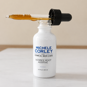 Michele Corley Clinical Skin Care Licorice Root Additive 1 oz dropper bottle open showing amber serum on marble surface.