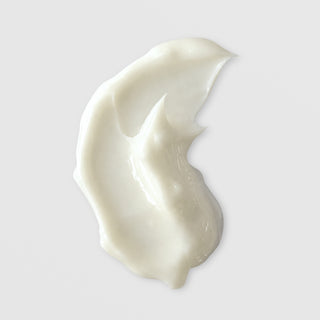 Michele Corley Peptide Rich and Radiant Eye Cream texture swatch showing rich glossy white eye cream formula on grey background.