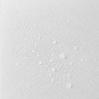 Michele Corley Plump Me Up Peptide Mist texture close-up showing ultra-fine clear mist droplets on white surface.
