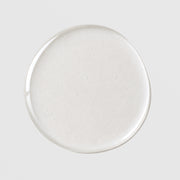 Michele Corley Pore Clearing Cleansing Oil texture drop showing lightweight milky white cleansing oil formula on grey background.