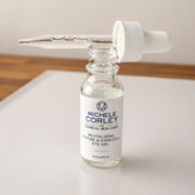 Michele Corley Clinical Skin Care Revitalizing Peptide and Stem Cell Eye Gel 0.5 oz clear glass dropper bottle open on marble surface.
