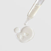 Michele Corley Revitalizing Peptide and Stem Cell Eye Gel texture showing lightweight clear gel drop from glass dropper on grey background.