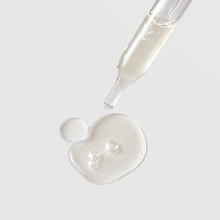 Michele Corley Revitalizing Peptide and Stem Cell Eye Gel texture showing lightweight clear gel drop from glass dropper on grey background.