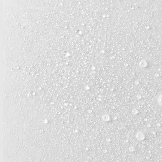 Macro close-up of fine clear water droplets scattered across a white surface, ranging from tiny micro-droplets to larger beads, depicting a freshly misted hypochlorous acid spray