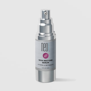 NeoGenesis Skin Restore Serum Vitamin A Retinoate 30 mL in a full chrome silver airless pump bottle with gray label and mauve pink botanical leaf icon on a light gray background
