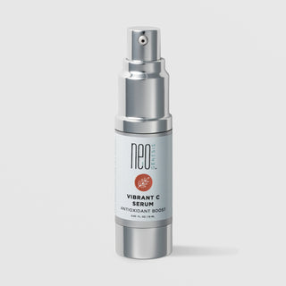 NeoGenesis Vibrant C Serum Antioxidant Boost 15 mL in a full chrome silver airless pump bottle with light gray label and terracotta botanical leaf icon on a light gray background