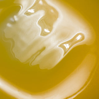 Macro closeup of NeoGenesis Vibrant C Serum showing rich golden yellow gel texture with creamy swirls on yellow background