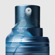 Close-up of Plated Skin Science CALM Serum pump nozzle dispensing lightweight clear gel serum with micro-bubbles on blue metallic bottle