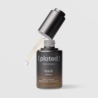 Close-up of Plated Hair Science Hair Serum dropper tip dispensing a single drop of lightweight golden serum