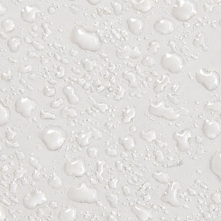 Close-up texture shot of Rhonda Allison Pro Youth 10 HA Hydra Mist showing lightweight clear serum droplets scattered across a white surface