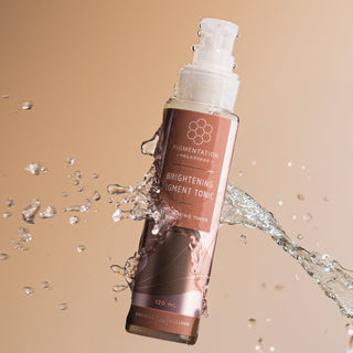Rhonda Allison Brightening Pigment Tonic with a splash of water on a beige backgound