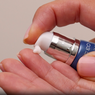Dispensing a small amount of GlyMed Plus CBD Regenerative Eye Cream from navy blue pump tube onto fingertip