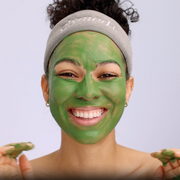Smiling woman wearing GlyMed Plus Hydrating Masque with Enzymes applied as a green face mask with a GlyMed headband