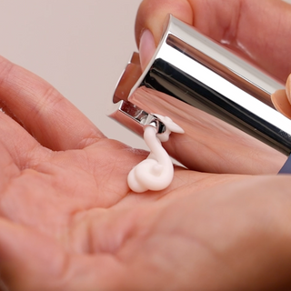 Dispensing GlyMed Plus Daily Repair Cream from silver pump applicator into palm of hand