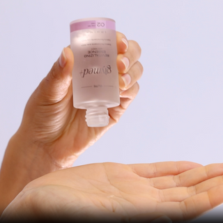 Model tipping GlyMed Plus Elite Revitalizing Essence with NAD+ bottle over open palm to dispense product