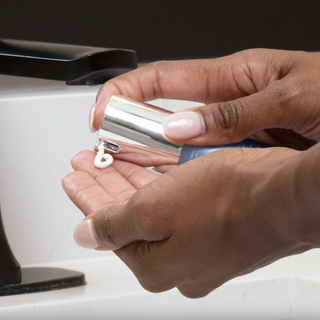 Model dispensing GlyMed Plus Vitamin E Cream from pump bottle into palm at bathroom sink