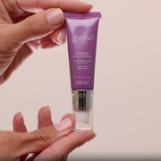 Hands holding GlyMed Plus Elite Firming Eye Cream 10mL purple pump tube