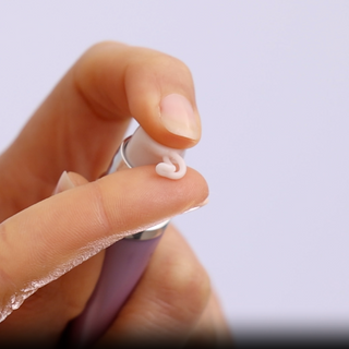 Dispensing a small amount of GlyMed Plus Lip Enhancer with Warming Actives from purple pump tube onto fingertip