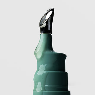 Close-up of Plated Skin Science Eye Serum teal bottle showing serum-coated cooling metal roller ball applicator tip