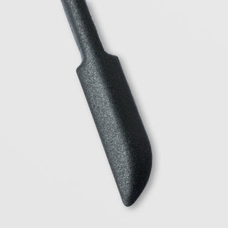 Close-up of the flat spatula end of the Sorella Apothecary Good to the Last Drop dual-ended tool on a light gray background