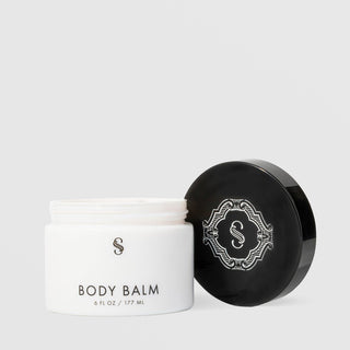 Sorella Apothecary Body Balm 6 fl oz open white jar showing cream texture beside black ornate lid on a light gray background