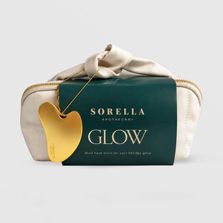 Sorella Apothecary Glow Holiday Set in cream knotted travel pouch with green sleeve and gold gua sha on a chain