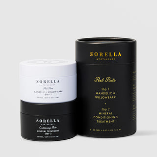 Sorella Apothecary Mandelic + Willow Bark Peel Pads two-step set with white Step 1 jar and black Step 2 jar beside the matte black cylindrical gift box on a light gray background