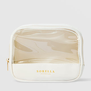 Sorella Apothecary clear window cosmetic bag with white base and gold zipper on a light gray background