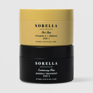 Sorella Apothecary Vitamin C + Ferulic Peel Pads two-step set with gold Step 1 jar stacked on black Step 2 Mineral Treatment jar on a light gray background