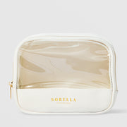 Sorella Apothecary branded travel cosmetic bag with a clear vinyl top panel, white faux leather base, gold zipper, and gold foil logo against a light gray background.