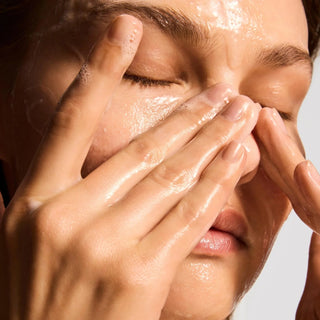 Close-up of person massaging iS Clinical Cleansing Complex lather onto wet face with both hands