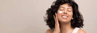 Woman smiling with skincare cream applied to her cheek — Art of Skin Care Clear Skin Coaching