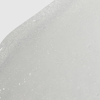 Close-up of Hale & Hush Refine Polish showing a clear gel exfoliant texture with fine white exfoliating particles on a light gray background
