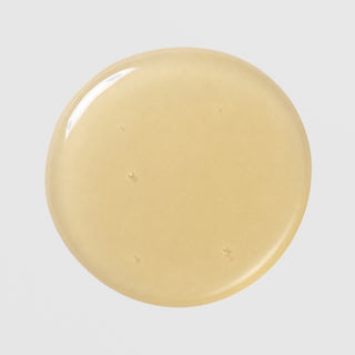 Close-up of Hale & Hush Rare Mandelic Serum showing a smooth, golden-yellow gel serum texture on a light gray background