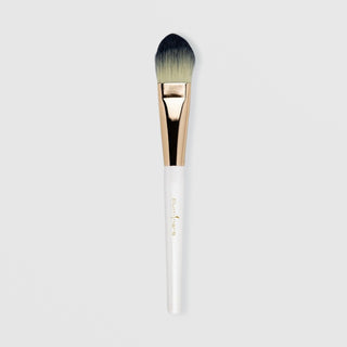 Illuminare foundation brush with white handle, rose gold ferrule, and dense tapered synthetic bristles in cream and charcoal tips