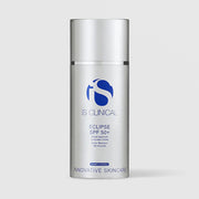 iS Clinical Eclipse SPF 50+ broad spectrum sunscreen crème in a silver airless pump bottle, cap removed, on a light gray background