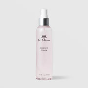 Le Mieux Essence Toner in a 6oz clear glass spray bottle with silver pump top and light pink formula visible through the bottle on a light gray background