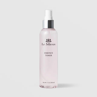 Le Mieux Essence Toner in a 6oz clear glass spray bottle with silver pump top and light pink formula visible through the bottle on a light gray background