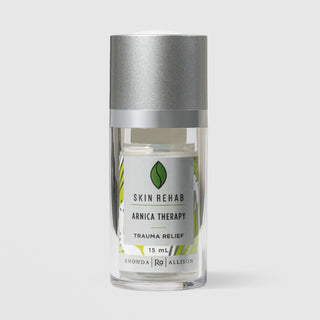 Rhonda Allison Skin Rehab Arnica Therapy Trauma Relief serum in a 15mL clear airless pump bottle with silver cap and green leaf logo on a light gray background
