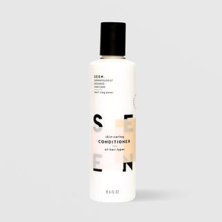 SEEN Skin-Caring Conditioner (8.6 fl oz) in a white bottle with a black flip cap and bold SEEN lettering accented by a warm tan color block, labeled dermatologist designed and suitable for all hair types, displayed against a light gray background.